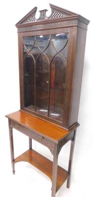 An Edwardian mahogany display cabinet, stamped Hampton & Sons London, 1825, the top with a pierced shaped crest above a single lazed door, decorated with blind fret, the base with a frieze drawer, reeded supports with under tier, (AF), 77cm wide.