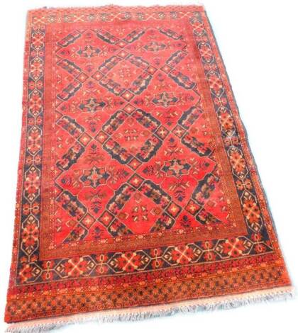 A Persian style rug, with a design of medallions on a red ground with various one wide and two narrow borders. 129cm x 190cm.