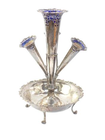 An Edward VII silver epergne, of four trumpet form, with four Bristol Blue glass flower holders, with pierced scrolling foliate decoration, raised on a circular bowl with a gadrooned rococo C scroll rim, raised on four scroll feet, William Hutton & Sons L