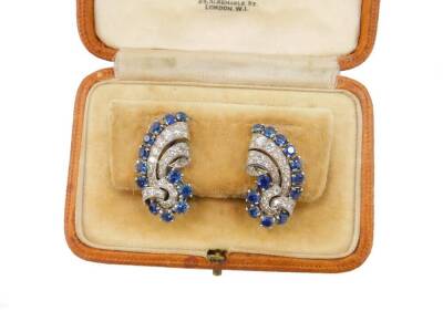 A pair of Garrard & Company mid 20thC sapphire and diamond ear or lapel clips, of scrolling form set in white metal, engraved Garrard London, cased, 14.3g all in. - 5