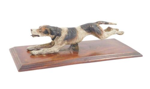 A Continental cold painted bronze figure of a running hound, on a brass spring mounted wooden base, 25cm L.