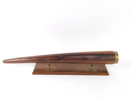 An oversized lignum vitae fid, brass capped, on a brass surmounted oak plinth, 92.5cm L.