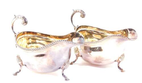 A pair of silver sauce boats, with a gadrooned rim and scroll handle, raised on three hoof feet, London 1960, 11.02oz.