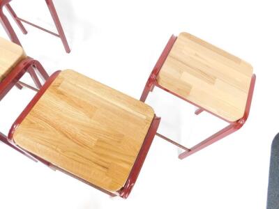 A set of four burgundy metal laboratory stools, with oak seats and metal cross bars, each 64cm H. - 2