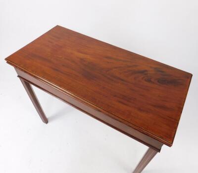 A George III mahogany fold over tea table, raised on fluted square legs, 73cm H, 92cm W, 42.5cm D. - 2