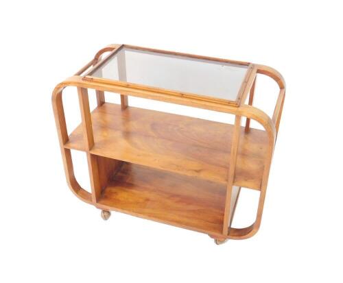 An Art Deco oval walnut cocktail drinks trolley, two tier with a glass inset top, raised on castors, 70.5cm H, 84cm W, 38cm D.