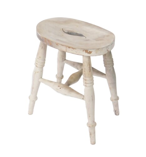 A late 19thC white painted beech blacksmith's stool, the oval seat raised on turned legs, united by an H frame stretcher.