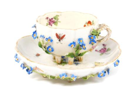 A 19thC Dresden porcelain miniature tea cup and saucer, painted and encrusted with flowers, painted 'D' mark.