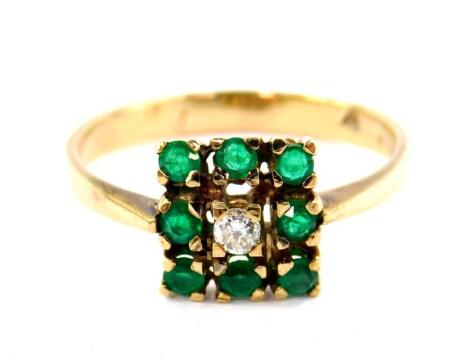 A 9ct gold emerald and diamond ring, set with a central diamond in a surround of eight emeralds, in a square design, size R, 2.5g all in.