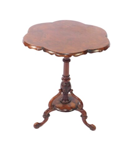 A Victorian burr walnut occasional table, the rounded six sided top, raised on a turned and leaf carved column, over a circular base and three double scroll cabriole legs, 73.5cm H, 61cm Dia.