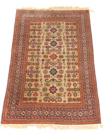 A Kuba rug, decorated with dragons, floral motifs and scrolls, against a cream ground within a floral patterned red border, 225cm x 140cm.