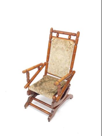 A Victorian pine American rocking chair, with turned frame, floral upholstered seat and back, on later castors.