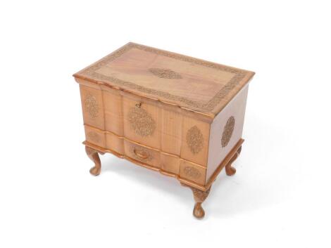 An Indian hardwood serpentine sewing chest, with floral and foliate carving, the hinged lid opening to reveal a fitted interior, over a frieze drawer, raised on cabriole legs, 45cm H, 54cm W, 35cm D.