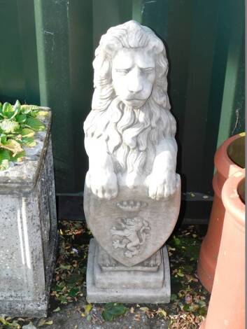 A concrete garden figure of a lion, modelled rampant holding an armorial shield, on a step square base, 85cm.