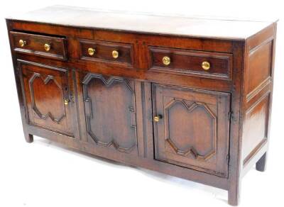 An 18thC oak dresser base, the rectangular plank top with a moulded edge above three frieze drawers each with brass handles and three panelled doors on stiles, adapted extensively internally, 83cm H, 152cm W, 46cm D.