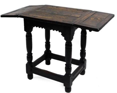 A late 17thC oak drop leaf table, the rectangular top with fruitwood inlay of roundels and cross-bands, set in flat panels, with a dog tooth type carved arch apron on turned supports with stretchers and bun feet, 67cm H, 97cm W, 47cm D.