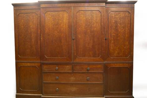 A fine early 19thC plum pudding mahogany breakfront wardrobe compactum in the manner of Gillows of Lancaster, having moulded cornice over an arrangement of two full length doors flanking a centred two doors over two short and two long graduated drawers w