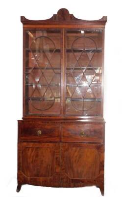 A George III mahogany secretaire bookcase, with a stepped arch pediment with satinwood stringing, flame frieze over two tall hour glass and diamond shaped astragal doors, the fall front secretaire drawer having satinwood and ebony stringing with flamed ca