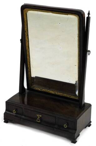 An 18thC walnut swing frame dressing table mirror, the rectangular bevel plate surrounded by a reeded slip, on tapering supports headed by turned brass finials, the base with three frieze drawers on ogee bracket feet.