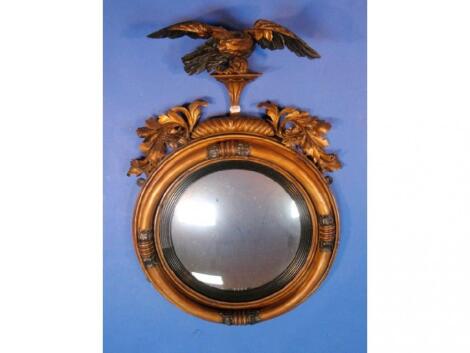 A Regency convex wall mirror in a circular gilt plaster frame with ebonised