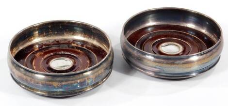 A pair of modern silver wine coasters, of plain circular design with turned wooden base and central boss, Sheffield 2000, 13cm Dia.