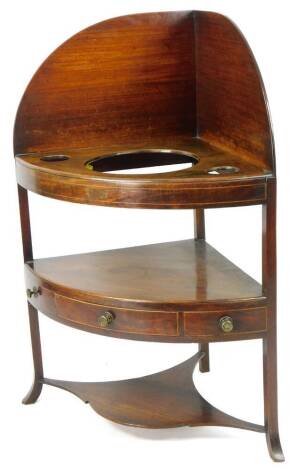 A principally George III mahogany corner wash stand, with openings for a bowl and two beakers, raised above an arrangement of three drawers on sabre stiles joined by a carved undertier, 109cm H, 77cm W, 53cm D.