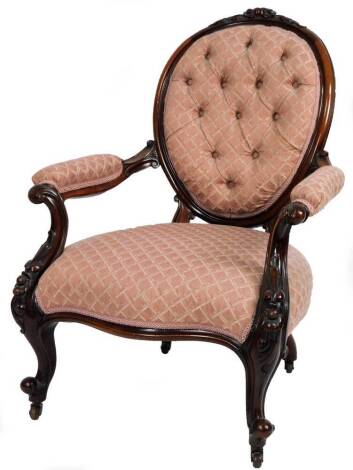 A Victorian mahogany spoon back armchair, with overstuffed arms and deep serpentine seat, with carved scroll and floral arm supports on cabriole legs terminating in castors, 97cm H.