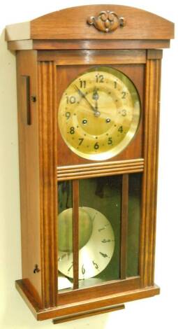 A mid 20thC oak cased wall clock, with fixed pediment, fluted sides and glazed front door, before a 19cm Dia. brass coloured Arabic dial with 8-day chiming movement, 67cm H.