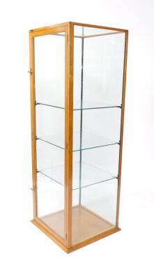 An early 20thC oak shop display cabinet, of square section, with glass top and four glass sides, the door opening to reveal three shelves, raised on a plinth base, 170cm H, 60.5cm W, 59.5cm D.