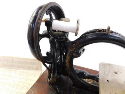 A late 19thC Wilcox & Gibbs sewing machine, gilt decorated black metal on a wooden base, together with spare needles and typed instructions. - 2