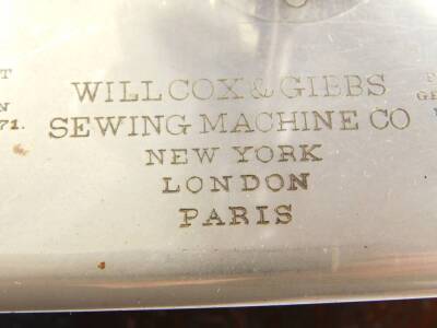 A late 19thC Wilcox & Gibbs sewing machine, gilt decorated black metal on a wooden base, together with spare needles and typed instructions. - 3