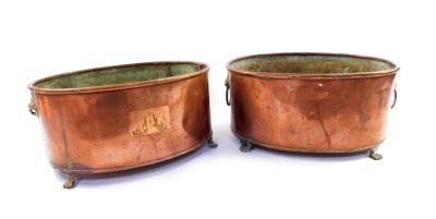 A pair of oval copper planters, with brass lion's head and ring handles, raised on lion's paw feet, 15cm H, 33cm L. (AF)