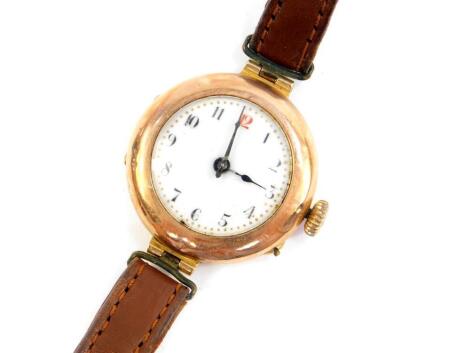 An early 20thC lady's 9ct gold circular cased wristwatch, white enamel dial bearing Arabic numerals, Swiss movement, on a leather strap, 18.2g all in.