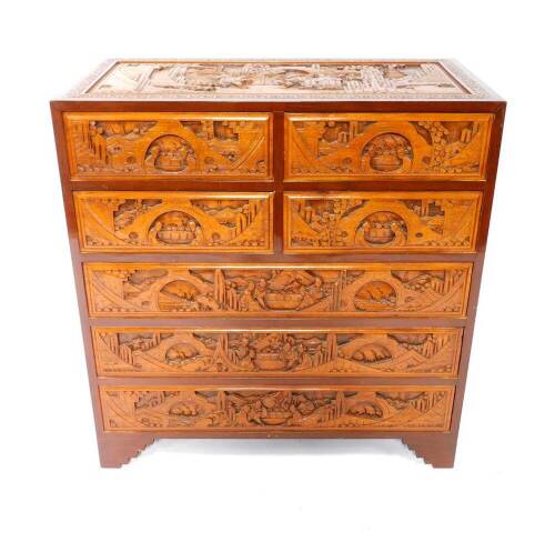 A Chinese hardwood chest of drawers, profusely carved with buildings, trees and figures, with four short over three long drawers, raised on bracket feet, 106.5cm H, 101.5cm W, 50.5cm D.