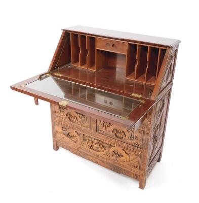 A Chinese hardwood bureau, profusely carved with buildings, trees and figures, the fall flap opening to reveal a central drawer and recesses, over four short and one long drawer, raised on square legs, 107cm H, 91cm W, 41.5cm D. - 2