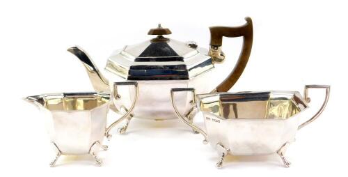 A George V silver three piece tea set, of octagonal form, raised on four paw feet, comprising tea pot, sugar bowl and cream jug, Sheffield 1933, 32.06oz all in.