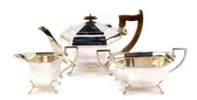 A George V silver three piece tea set, of octagonal form, raised on four paw feet, comprising tea pot, sugar bowl and cream jug, Sheffield 1933, 32.06oz all in.