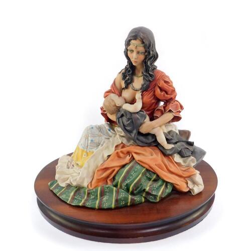 A Capo di Monte porcelain figure group, of a seated mother suckling her baby, raised on an oval wooden base, printed mark, 35cm H.