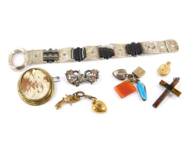 A Victorian Scottish silver and agate bracelet, continental shell cameo brooch decorated with figures in a village setting, Victorian silver entwined heart and swallow brooch, agate set cross and sundry gold and other charms. (qty)