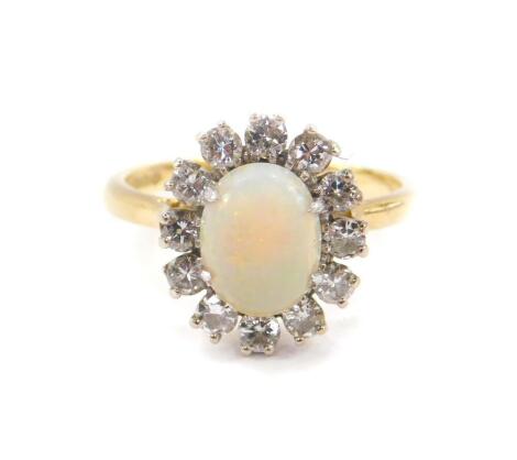 An 18ct gold opal and diamond ring, the opal set in a surround of twelve brilliant cut diamonds, approx 0.75cts, size P, 5.0g all in.