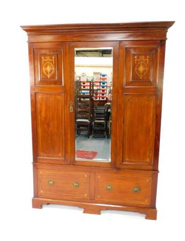 An Edwardian mahogany and inlaid double wardrobe, the outswept pediment over a single mirrored door, opening to reveal a hanging rail, over two drawers, raised on ogee bracket feet, 205cm H, 151cm W, 48.5cm D.