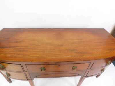 A George III mahogany bow front sideboard, with line inlay, and brass lion head and ring handles, having one long over one cushion drawer, flanked by two doors, one holding a cellarette, raised on tapering square legs and collared feet, 191cm H, 82cm W, - 2