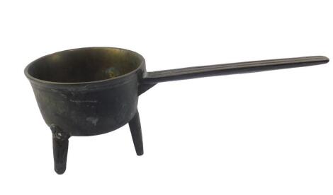 A Georgian bronze saucepan, with fluted handle, raised on tripod feet, 53cm L.