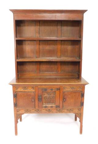 A Victorian oak dresser, the outswept pediment over a two shelf plate rack, above three carved doors, centre door with iron strap work raised on square legs, 208cm H, 126.5cm W, 55.5cm D.