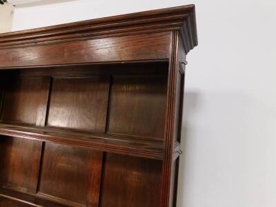 A Victorian oak dresser, the outswept pediment over a two shelf plate rack, above three carved doors, centre door with iron strap work raised on square legs, 208cm H, 126.5cm W, 55.5cm D. - 3