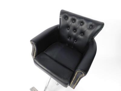 Two black leather barber's chairs, each with button back, raised on a metal frame and five point star base, with footrest and adjustable seat lever. - 2