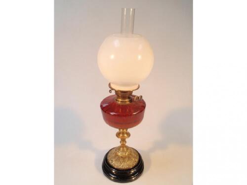 A Victorian oil lamp with a ruby glass reservoir