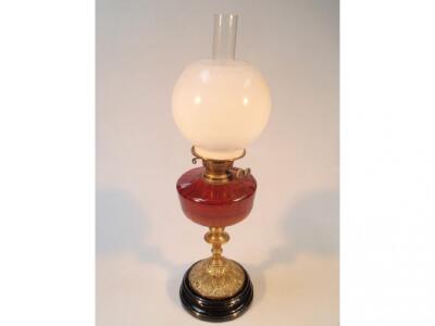 A Victorian oil lamp with a ruby glass reservoir