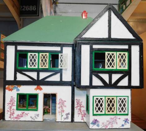 A 20thC wooden double fronted doll's house, modelled as a Mock Tudor house, together with furniture, etc, 56cm H, 60cm W, 45cm D.