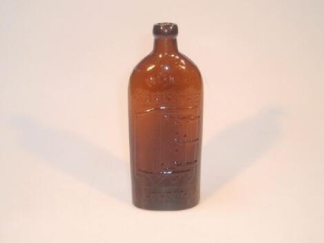 A Victorian brown glass bottle moulded in relief with a safe on wheels